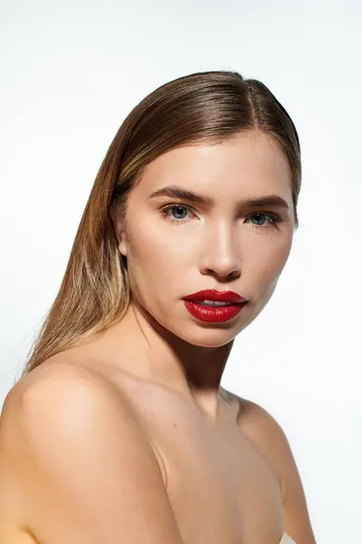 Eine junge Frau mit kräftigen roten Lippen und markanten Gesichtszügen sticht vor weichem Hintergrund hervor.. — Stockfoto