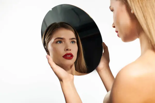 Una giovane donna elegante con belle caratteristiche guarda pensieroso in uno specchio rotondo. — Foto stock