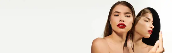 Mujer joven con el pelo largo admira a sí misma, mientras que destaca el maquillaje pulido y el estilo elegante - foto de stock