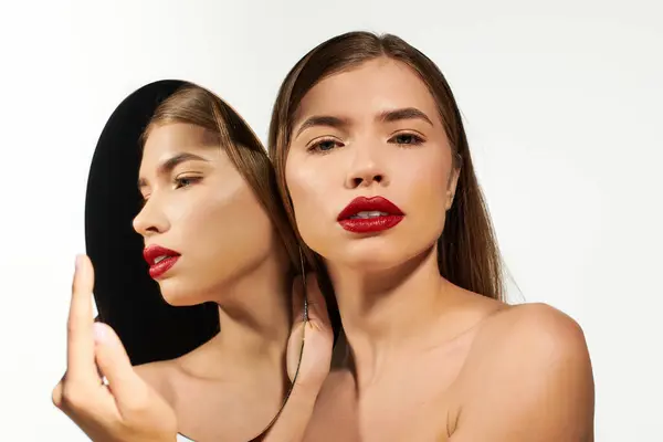 Una giovane donna dalle labbra rosse audaci ammira il suo stile elegante allo specchio. — Foto stock