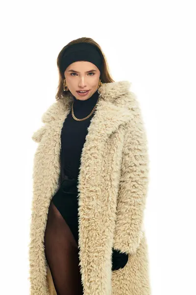 Giovane donna mette in mostra il suo abito invernale chic con un cappotto soffice e una posa elegante. — Foto stock