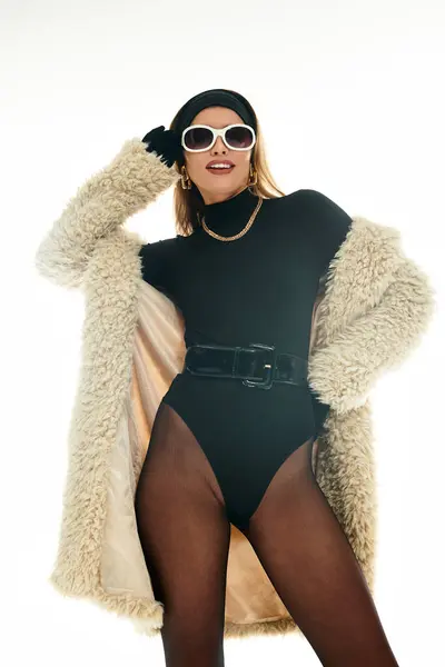 Mulher jovem confiante posa em um bodysuit preto chique e casaco na moda, exalando elegância moderna. — Fotografia de Stock
