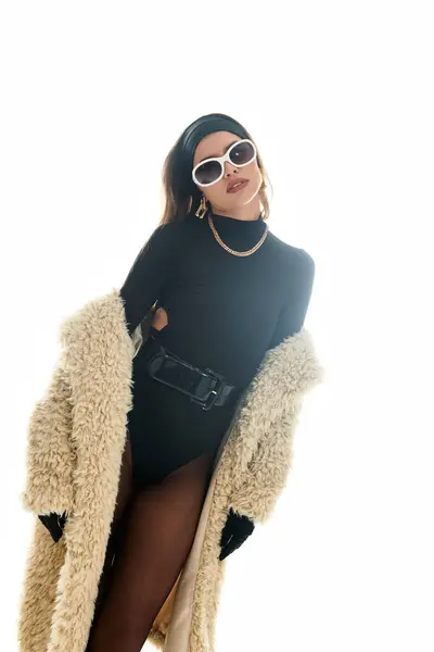 A young woman poses gracefully in a stylish bodysuit, fur coat, and striking accessories. — Stock Photo