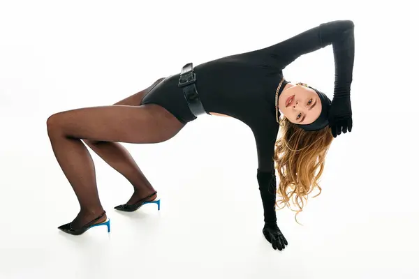 Uma jovem mulher em uma roupa preta chique se curva para trás, mostrando sua flexibilidade e graça. — Fotografia de Stock