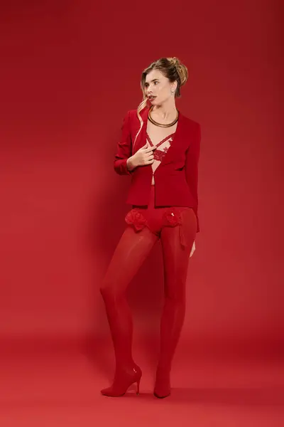 Confident young woman in a striking red outfit against a vibrant red background. — Stock Photo