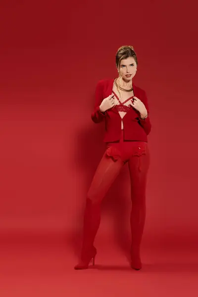 A young woman in a bold red outfit poses confidently against a matching background. — Stock Photo