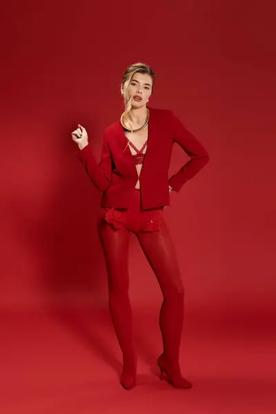 Mujer joven y confiada muestra su vibrante atuendo rojo en un entorno cautivador. - foto de stock