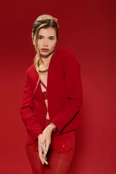 Beautiful young woman showcases her fashionable red ensemble while posing in a vibrant studio. — Stock Photo