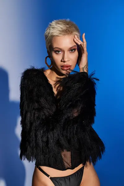 Young woman showcases modern beauty and confidence in chic fashion against a vibrant blue backdrop. — Stock Photo