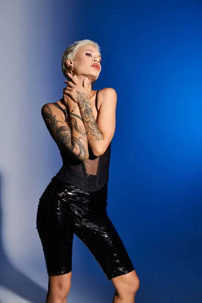 A fashionable young woman exudes confidence while posing against a striking blue backdrop. — Stock Photo