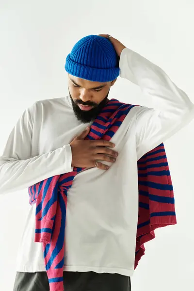 Un bel homme en chemise blanche et pull rayé drapé sur son épaule semble réfléchi. — Photo de stock