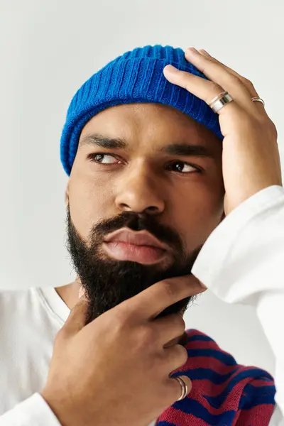 Beau jeune homme dans un bonnet bleu et tenue décontractée pose avec soin sur un fond de lumière. — Photo de stock