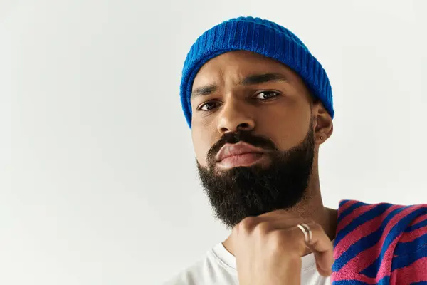 A young man in a stylish blue beanie and colorful stripes exudes confidence. — Stock Photo