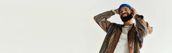 Красивый молодой человек в стильной одежде радостно позирует с руками на голове в ярком пространстве. — стоковое фото