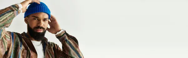 A young man in a colorful beanie and stylish outfit showcases his individuality. — Stock Photo