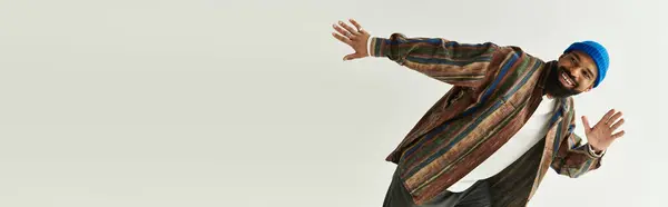 Stylish man playfully poses in a minimalist setting, expressing vibrant fashion and confidence. — Stock Photo