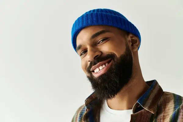 A fashionable young man with a full beard flashes a cheerful smile while dressed in casual attire. — Stock Photo