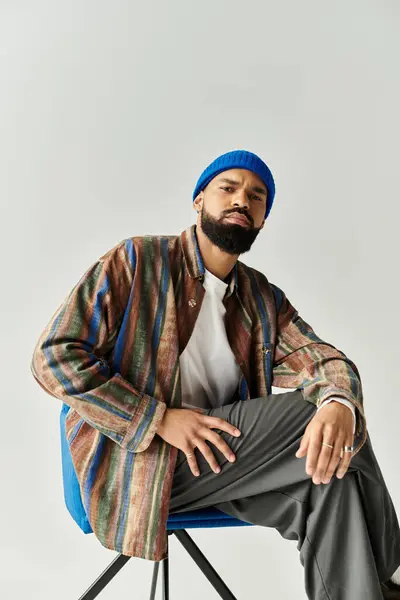 A handsome male model effortlessly showcases trendy attire while seated. — Stock Photo
