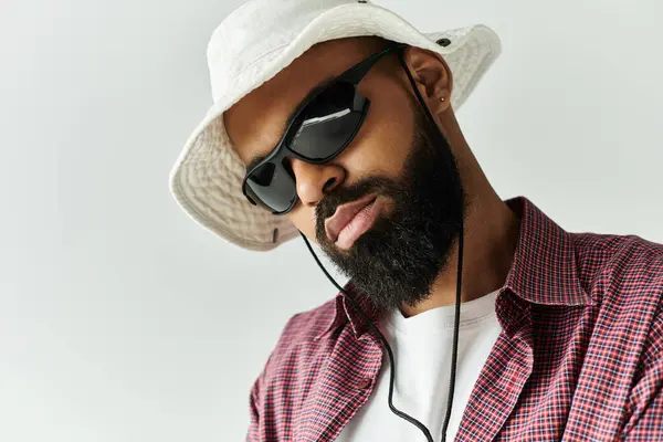Un giovane alla moda mette in mostra il suo stile unico con occhiali da sole e un cappello, incarnando fiducia fresca. — Foto stock