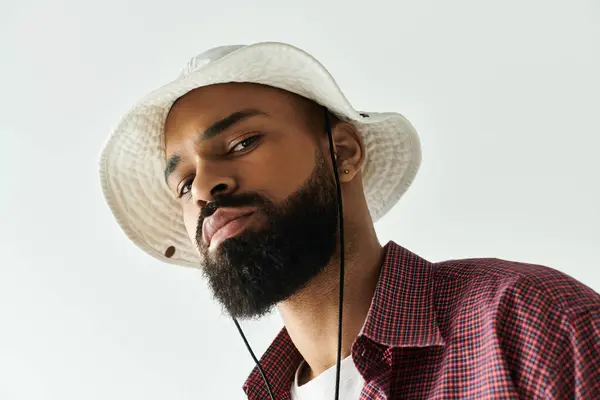 A fashionable young man poses with a serious expression while wearing a stylish bucket hat. — Stock Photo