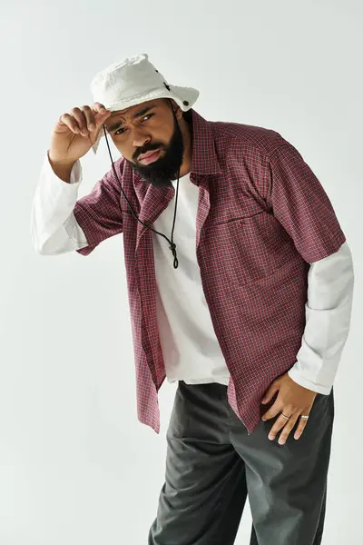 Handsome young man poses confidently in a stylish outfit, set against a simple backdrop. — Stock Photo