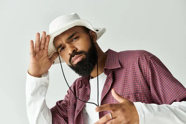 A trendy young man in a bucket hat strikes a cool, playful pose in a chic setting. — Stock Photo
