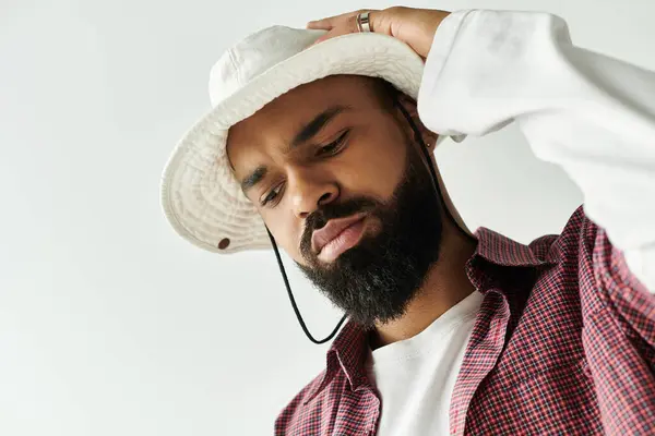 A young man flaunts his style in a bucket hat and checkered shirt in a bright room. — Stock Photo