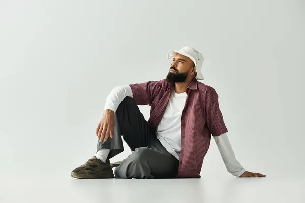 Stylish man sits casually on the floor, showcasing a confident demeanor and modern fashion. — Stock Photo