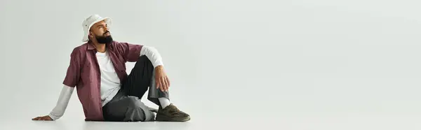 A stylish young man relaxes on the floor, deep in thought and showcasing his fashion. — Stock Photo