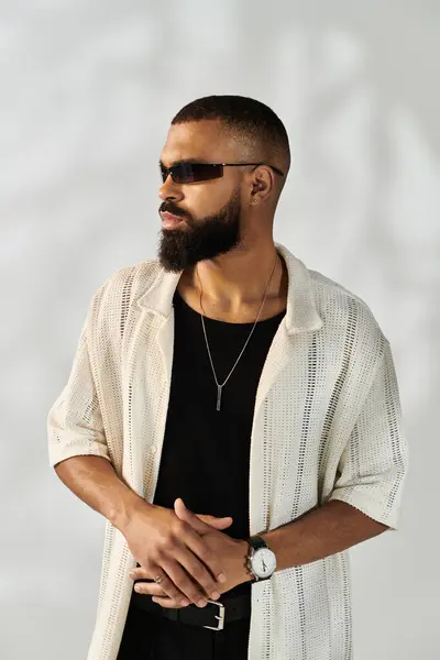 Stylish man poses confidently in a chic outfit, exuding charisma in a modern studio. — Stock Photo