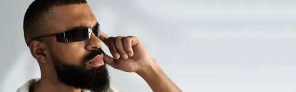 A stylish young man with a well groomed beard and trendy sunglasses displaying his look. — Stock Photo