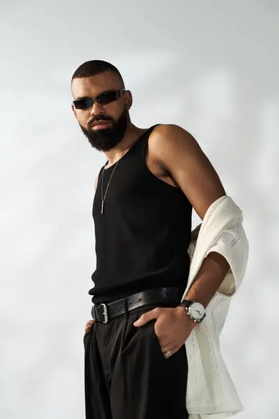 A stylish young man poses confidently against a neutral backdrop, showing modern fashion. — Stock Photo