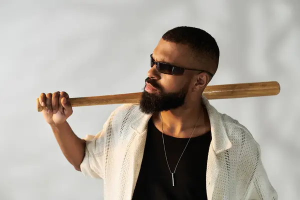 Fiducioso giovane mostra il suo stile con una mazza da baseball su uno sfondo semplice. — Foto stock