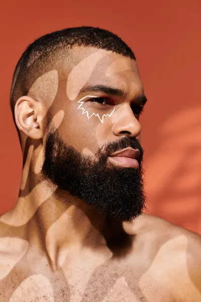 Young fashion forward man showcases a striking face design while exuding charm and confidence. — Stock Photo