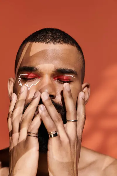 A young man expresses his unique style with striking makeup and accessories, exuding confidence. — Stock Photo