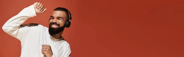 A stylish young man dances joyfully to music in warm, vibrant surroundings. — Stock Photo