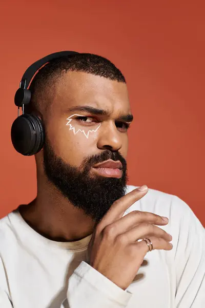 Stylish man with headphones flaunting artistic facial design, exuding confidence. — Stock Photo