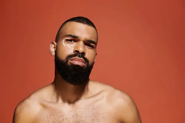 Fashion forward young man displays unique facial paint amid a vibrant backdrop. — Stock Photo