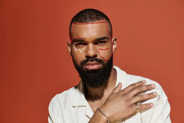 Young man showcases his fashion sense with bold facial art and a relaxed pose against vivid color. — Stock Photo
