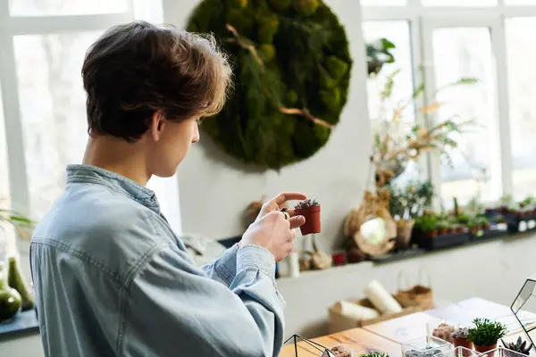 Young artist engages with creativity while examining a small plant in an inspiring art studio. — Stock Photo