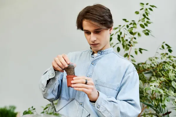 Young man engages in creative exploration while nurturing plants in an inspiring art studio — Stock Photo