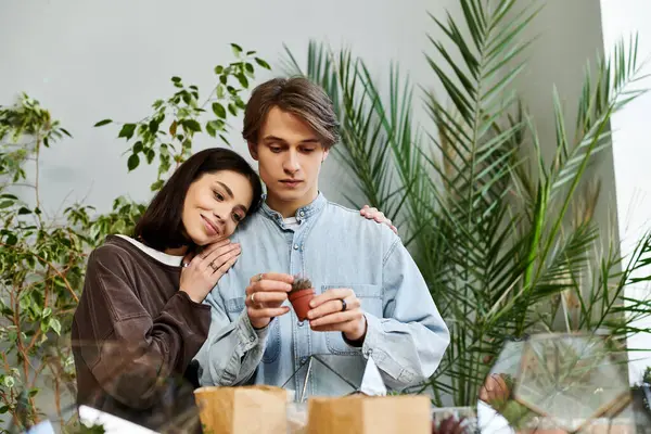 Loving couple in a bright art studio express creativity and inspiration while nurturing plants. — Stock Photo