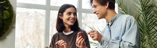 Kreative Paare tauschen sich fröhlich zwischen kreativen Materialien und Pflanzen aus. — Stockfoto