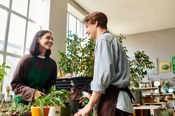 Creative couple joyfully collaborate in a vibrant studio, surrounded by greenery and artwork. — Stock Photo
