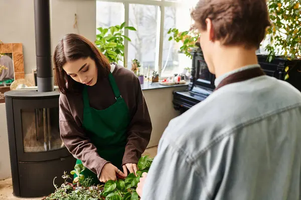 Young couple collaborate in a vibrant art studio, nurturing plants and exchanging creative ideas. — Stock Photo