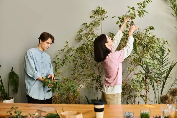 Young couple create art while caring for plants in a vibrant studio setting. — Stock Photo