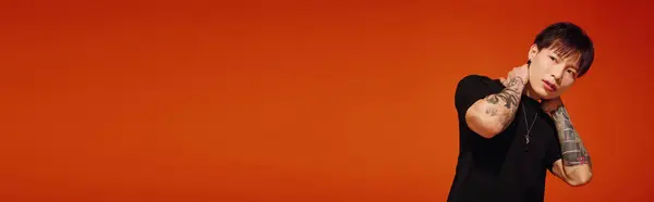 Jeune homme beau pose élégamment avec une main sur son cou, entouré d'un cadre orange audacieux. — Photo de stock