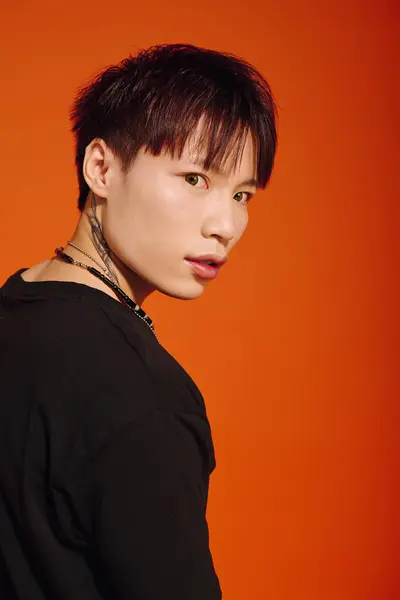 A young fashionable Asian man looks back with a confident expression, showcasing his stylish look. — Stock Photo