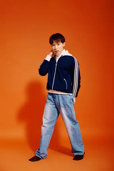 Young, attractive Asian man poses confidently against a bright orange background. — Stock Photo