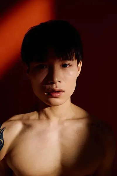 Young and handsome Asian man stands boldly, showing off his stylish look in soft lighting. — Stock Photo